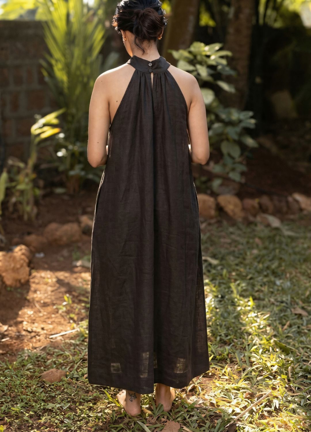 Back view of a black sleeveless halter-neck maxi dress with a flowing relaxed silhouette