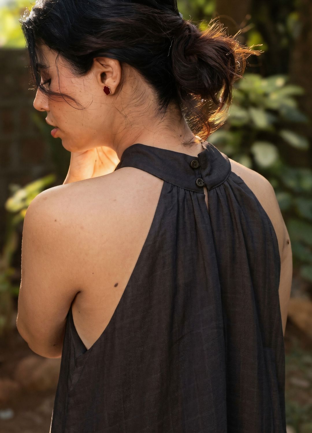 Back view of a black sleeveless halter-neck maxi dress with a flowing relaxed silhouette